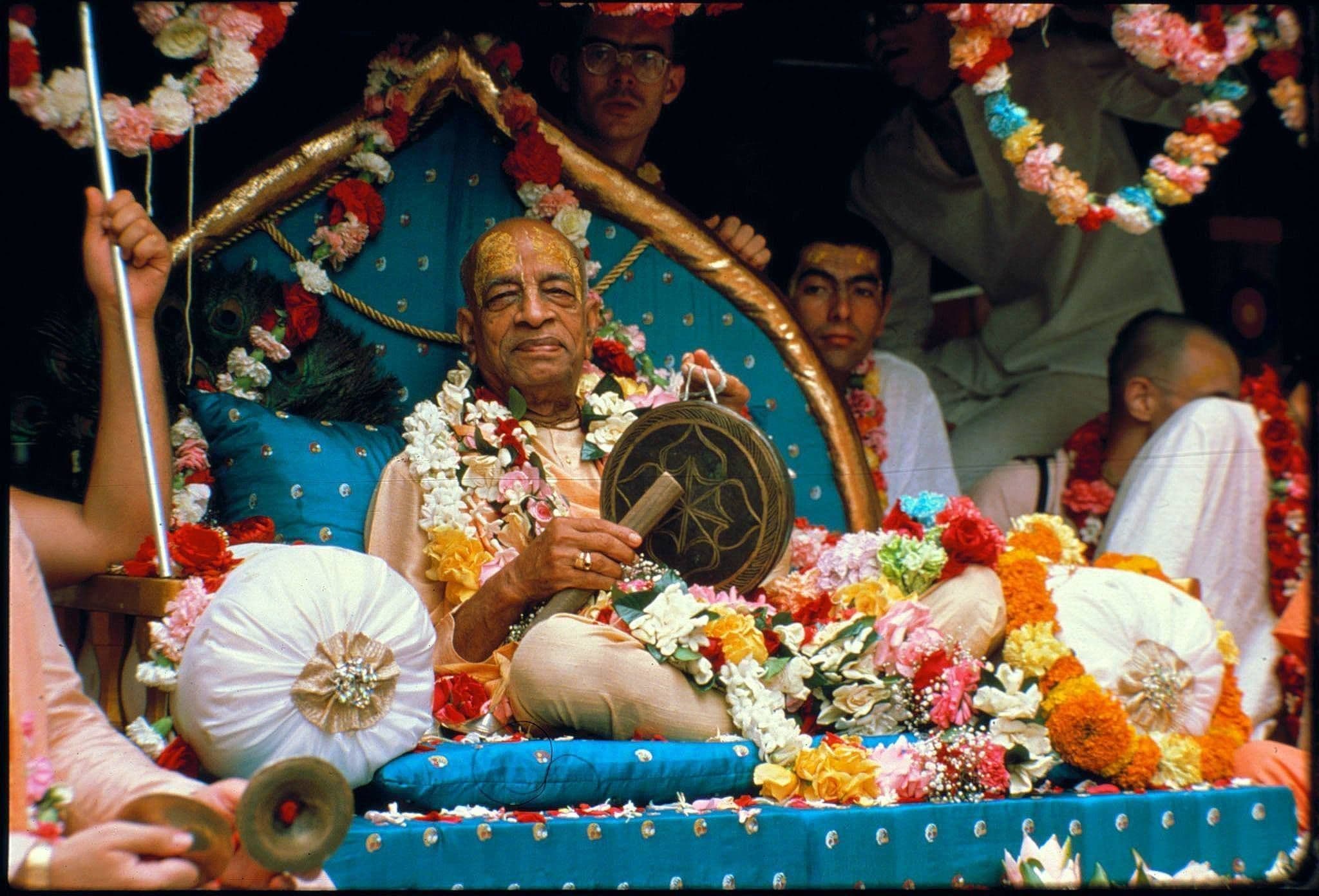 Devotees gathered in kirtan around a garlanded seat